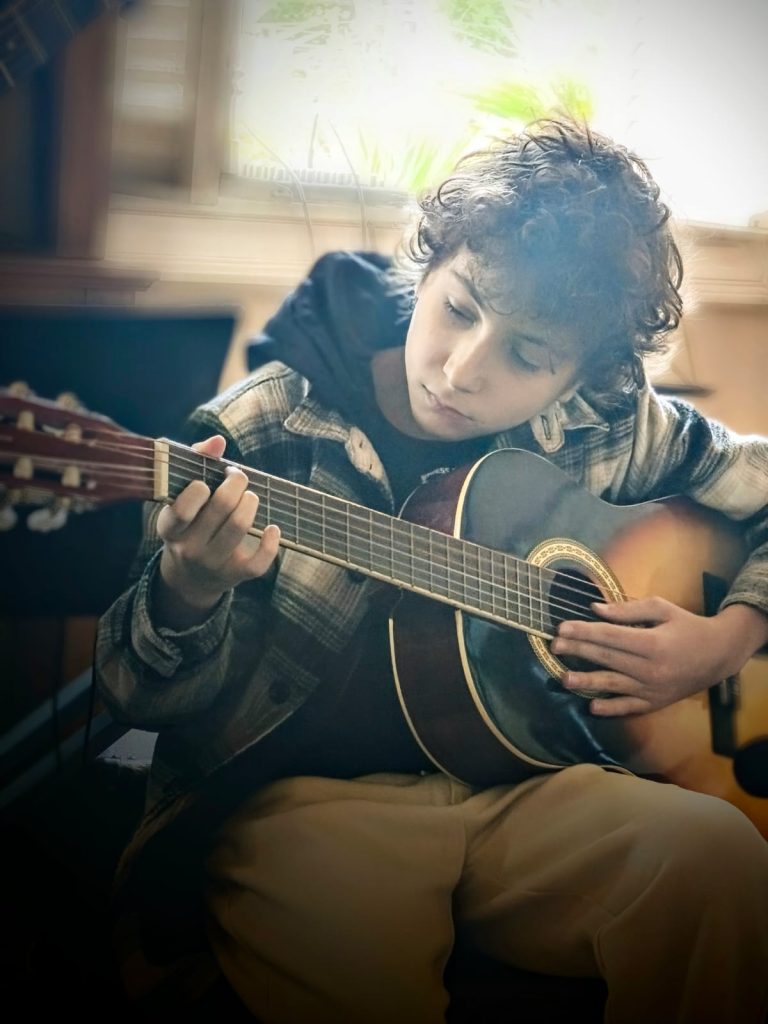 niño aprendiendo guitarra

